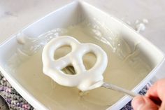 someone is using a spoon to dip something in some kind of liquid that looks like a pretzel