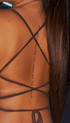 the back of a woman's neck with a tattoo on her left side and an x in the middle