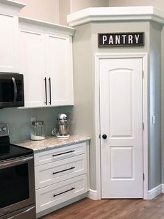 a kitchen with white cabinets and stainless steel appliances, including a pantry sign on the door