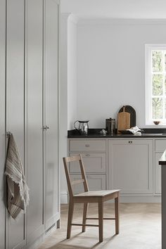 a kitchen with white cabinets and black counter tops, along with a wooden dining chair