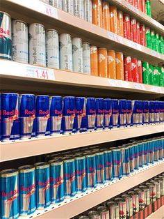 many cans of soda are on shelves in a grocery store, one is blue and the other is red