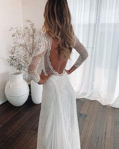 the back of a woman's wedding dress in front of a white vase and window