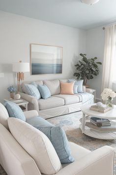 a living room filled with white furniture and blue pillows on top of it's couches