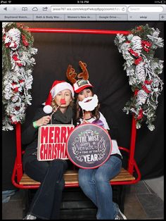 two women sitting on a bench with christmas wreaths and signs in front of them