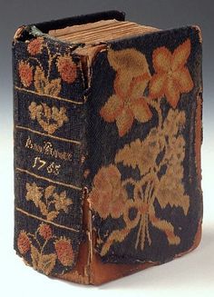 an old book with flowers on it sitting on a white table next to a gray background