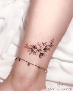 a woman's foot with a flower tattoo on her left ankle and a chain around it