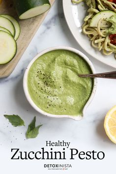 healthy zucchini pesto in a bowl next to sliced cucumbers