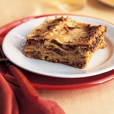 a white plate topped with three pieces of lasagna on top of a wooden table