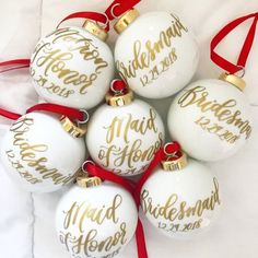 six white and gold christmas ornaments with red ribbon on them, arranged in a pyramid