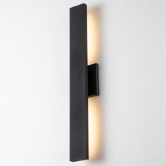 a black wall mounted light on the side of a white wall