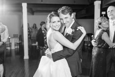 a bride and groom dance together on the dance floor at their wedding reception in black and white