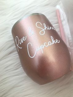 a pink and shiny cup with writing on it next to a toothbrush in a bag