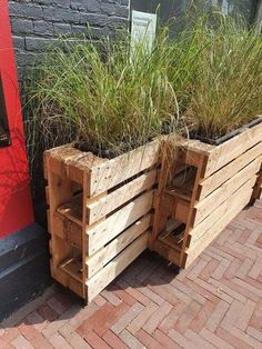 two wooden planters with grass growing out of them on the side of a building