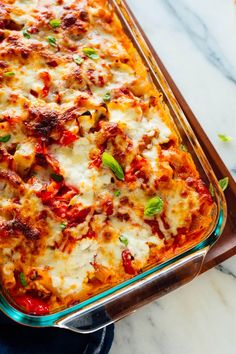 a casserole dish with meat, cheese and vegetables in it on a marble counter top