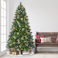 a decorated christmas tree sitting next to a wooden bench in a room with white walls