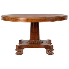 an oval dining table with carved legs and a wooden center piece on one end,