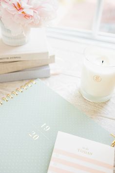 a table with a notebook, candle and flowers on it