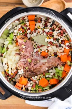 a pot filled with meat and vegetables on top of a wooden table