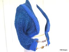 a crocheted blue shawl is shown on a mannequin