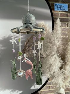 a stuffed animal is hanging from a wind chime with seashells and starfish