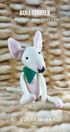 a crochet mouse with a green scarf on it's neck sitting on a fur surface