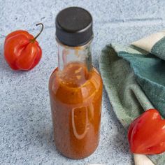 a jar filled with sauce next to two tomatoes on a towel and spoons in front of it