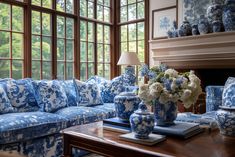 a living room filled with blue and white furniture next to a fire place covered in vases