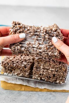 a person holding up some brownies on top of a cooling rack