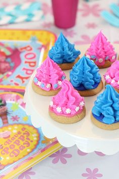 there are cookies decorated with blue and pink frosting on a cake platter next to other desserts