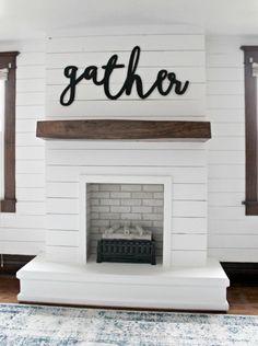 a white fireplace with the word gather painted on it's mantle in a living room