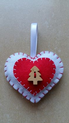 a red and white heart shaped ornament with a wooden christmas tree on it