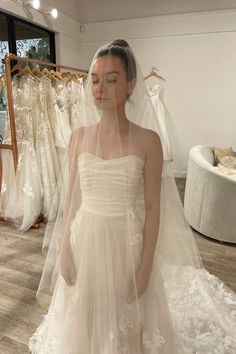 a woman standing in front of a wedding dress