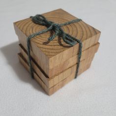 three wooden boxes tied with twine on top of each other, sitting on a white surface