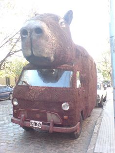 a very large stuffed animal sitting on top of a car