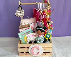 a wooden crate filled with baby items on top of a white sheet covered floor next to a purple wall