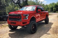 a red truck is parked in the dirt