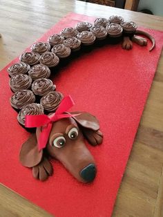 a dog made out of cupcakes sitting on top of a red tablecloth