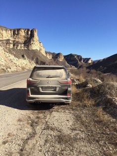 a car parked on the side of a road in front of some mountains and rocks