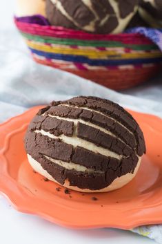 a chocolate cookie with white frosting on an orange plate