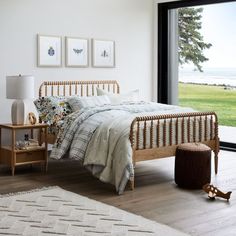 a bedroom with a bed, nightstand and window overlooking the grass field in front of it