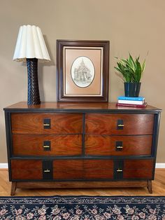 a wooden dresser sitting next to a lamp on top of a hard wood floor