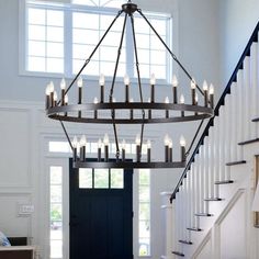 a large chandelier hanging from the ceiling in a room with stairs and windows