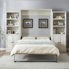 a white bed sitting in a bedroom next to a book shelf filled with books and vases