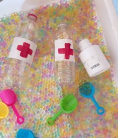 three plastic bottles with red cross on them and spoons next to eachother