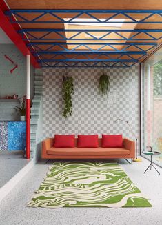 a living room with an orange couch and green rug on the floor in front of it