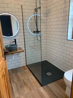 a bathroom with a glass shower stall and wooden flooring, along with a white toilet