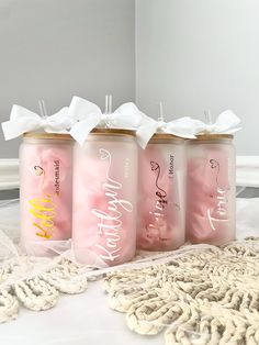 three pink and gold colored jars with white ribbons on them sitting on a lace doily