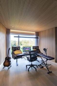 a recording studio with two guitars and sound equipment on the floor, in front of a large window