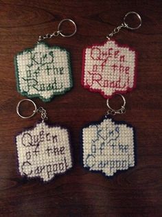 four cross stitch keychains on a wooden table