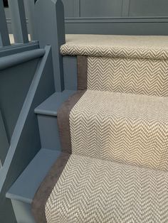 a carpeted staircase with grey handrails and beige carpet on the bottom step